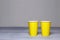 Mockup two yellow paper cups on grey background. Disposable coffe cup in trending color