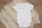 Mockup of white baby bodysuit on wood background. Blank baby clothes template mock up. Flat lay styled stock photo