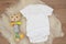 Mockup of white baby bodysuit on wood background. Blank baby clothes template mock up. Flat lay styled stock photo