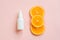 Mockup white cosmetic spray mini travel bottle and three sliced orange on pink background. Body mist, sanitizer, perfume,