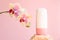 Mockup white cosmetic tube bottle with pink screw cap on stone and phalaenopsis orchid Octopus flowers  on pink background.