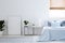 Mockup of white empty poster in simple hotel bedroom interior wi