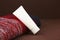 Mockup of white squeeze bottle plastic cosmetic tube for branding and Christmas or autumn red knitted sweater on brown background