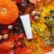 Mockup of white squeeze bottle plastic tube, pumpkin, magic lights and bright autumn leaves. Atmospheric fall flatlay. Clean