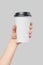 Mockup of women`s hand holding white paper large size cup with black cover