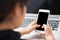 Mockup young businesswoman using smart mobile phone and laptop computer with screen blank on desk