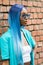 Model with blue hair wearing a white top and a turquoise jacket