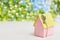 Model of cardboard house with a bow of twine and key against green bokeh background. house building, loan, real estate or buying