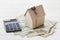 Model of cardboard house with key, calculator and cash dollars. House building, loan, real estate. Cost of public utilities.