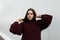 Model of a fashionable pretty young woman in a knitted stylish burgundy sweater posing on the street near a white building. Modern