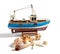 Model fishing boat with shells and starfishes on the white background