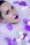 model girl with violet make-up in milk bath with violet flowers