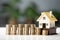 model home next to ascending stacks of coins representing an increasing loan