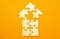 Model of a house on a uniform orange background for the concept of real estate loans. Close-up figure in the form of a