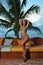 Model poses at tropical location with palm tree on background