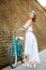 Model in romantic image poses near vintage bicycle, brick wall