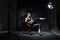 Model in spotlight posing on black leather chair in studio