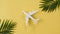Model of a Toy Airplane of White Color and Palm Leaves on a Yellow Background. Passenger Airplane Flies, Moves. Concept
