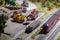 A model of a toy electric train drives along the rails past a sorting and freight station with firewood and wagons