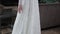 Model tries on elegant white wedding dress with long skirt