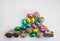 Models of toy excavator and loader, lot of chocolate eggs in colorful wrappers, quail eggs on light background