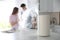 Modern air humidifier and blurred couple in kitchen