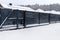 Modern anthracite panel fence with falling smeared snow during a snowstorm.