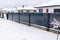 Modern anthracite panel fence with falling smeared snow during a snowstorm.