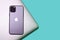 Modern Apple technology, metallic grey laptop MacBook Pro, purple smartphone iPhone 11 with three cameras on green, blue backgroun