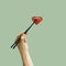 Modern artisan food concept. The man\'s hand holding high black chopsticks with red yummy heart shaped ravioli pastel green