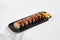 Modern asian food - sushi roll with eel on black plate on white concrete background. Canada maki with eel outside, avocado, cheese
