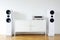 Modern audio stereo system with white speakers on bureau in modern interior.