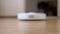 A Modern Automatic Robot Vacuum Cleaner Sweeps Debris on Floor in Room. Close up