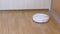 A Modern Automatic Robot Vacuum Cleaner Sweeps Debris on Floor in Room. Close up