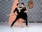 Modern ballet dancer couple in black jacket black trousers, black dress performing art jump element with background