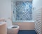 Modern bathroom with bath, toilet, niche in wall and basin unit, blue rubber floor and blue and white patchwork tiles