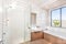 Modern bathroom with a faucet, water tub and a dark brown floor tiles