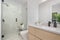 Modern bathroom featuring a white ceramic sink, a white toilet, and a glass-enclosed shower stall