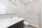 A modern bathroom with a wood cabinet and tiled shower.