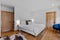 Modern bedroom with hardwood floors, a crisp white bed with a blue accent chair.