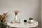 Modern beige ceramic vases with dry grass branches on white table near a black white wall backdrop. Copy space.Minimal Scandinavia