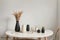 Modern beige ceramic vases with dry grass branches on white table near a black white wall backdrop. Copy space.Minimal Scandinavia