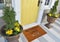 Modern beige Welcome members only zute doormat with key outside home with yellow flowers and leaves