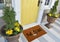 Modern beige Welcome zute doormat with axe outside home with yellow flowers and leaves