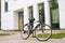 Modern bicycle standin on footplate in city street on blurred background of front door of apartment building, office