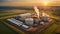 Modern biogas plant between several fields in rural region with sunset background, Bioenergy plant utilizing organic waste,