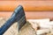 Modern black axe in the log and wooden chips after cutting firewood for winter near pile wooden house