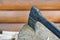 Modern black axe in the log and wooden chips after cutting firewood for winter near pile wooden house