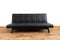 Modern black leather convertible sofa bed, wooden floor. Empty waiting room with a modern black sofa