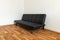 Modern black leather convertible sofa bed, wooden floor. Empty waiting room with a modern black sofa